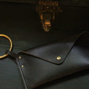 Leather wristlet with gold ring. Dark and moody lighting.